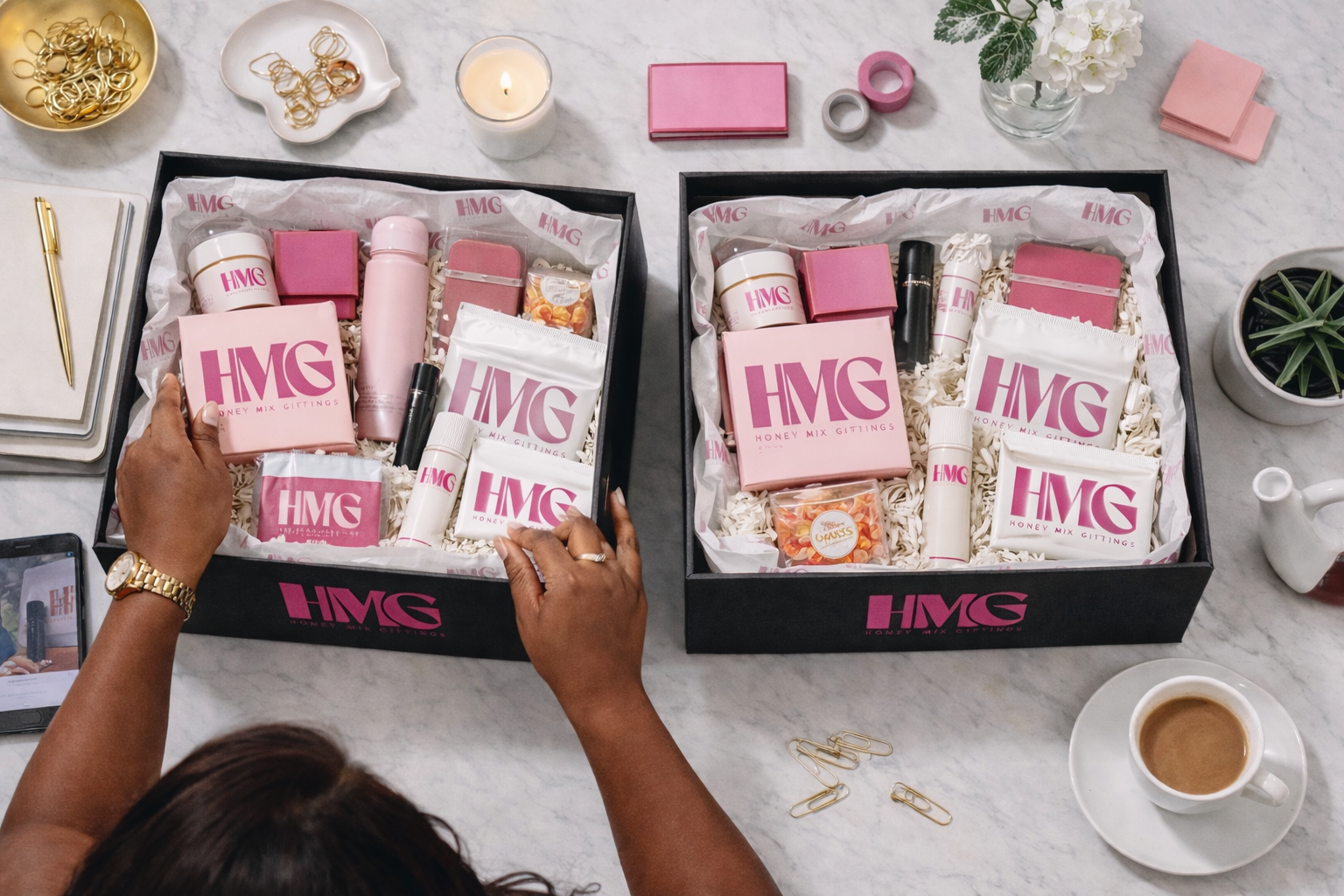 HMG branded gift boxes filled with curated pink and white products on a marble surface